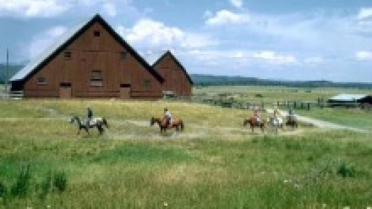 Riders crossing the meadow in front of the historic Railroad Ranch barns at Harriman State Park
