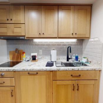 The compact kitchen featuring a stovetop, large sink, and plenty of cupboard space.