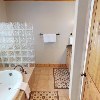 Located within the master bedroom is the ensuite bathroom with a standing shower, soaking tub, toilet, and mirror vanity.
