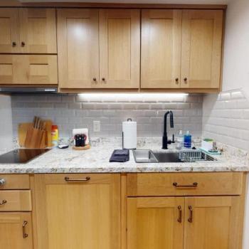 The compact kitchen featuring a stovetop, large sink, and plenty of cupboard space.