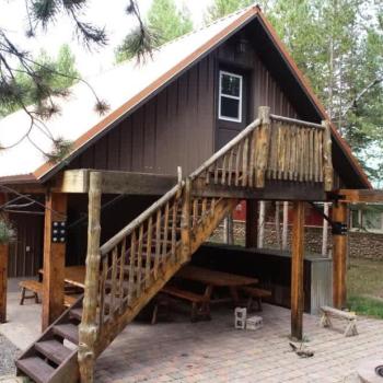 The property includes a separate guest suite above the garage, featuring a private balcony and a covered patio setup with picnic tables below.