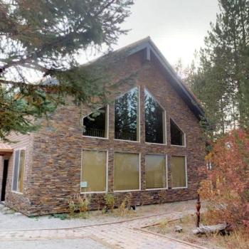 Welcome to North Big Springs Lodge! This stunning stone-accented cabin features beautiful geometric windows and is surrounded by lush, peaceful trees.