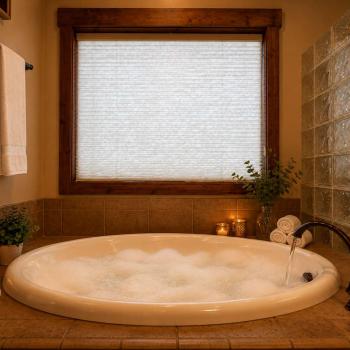 Indulge in a spa-like experience in the master bathroom, featuring a grand circular tub surrounded by warm candle light.