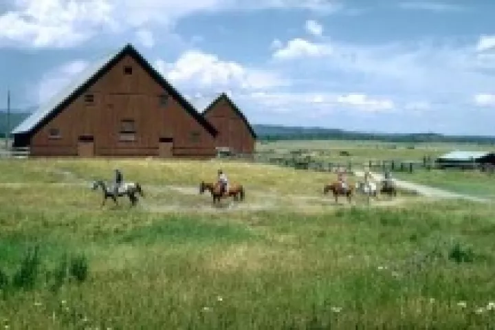 Riders crossing the meadow in front of the historic Railroad Ranch barns at Harriman State Park