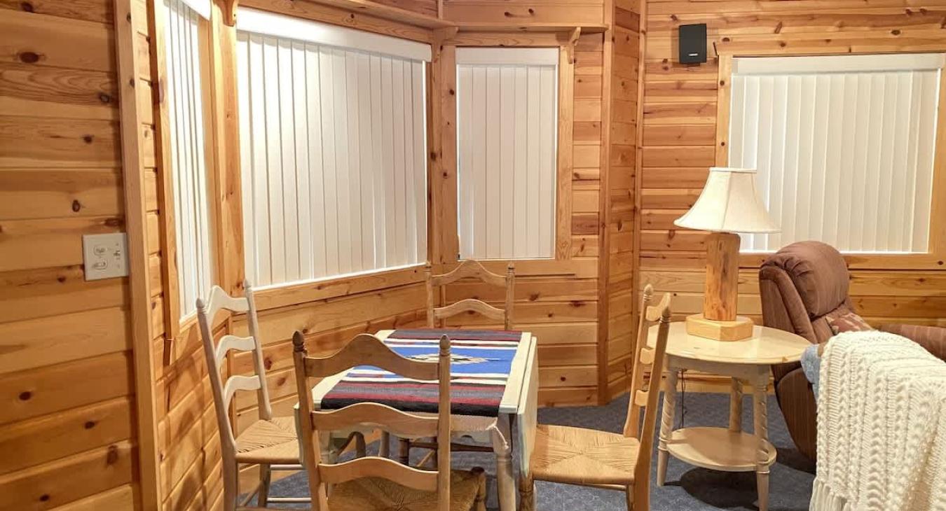 Large windows wrap around two walls, flooding the room with natural light during the day and offering beautiful views of the surrounding woods or snowfall.