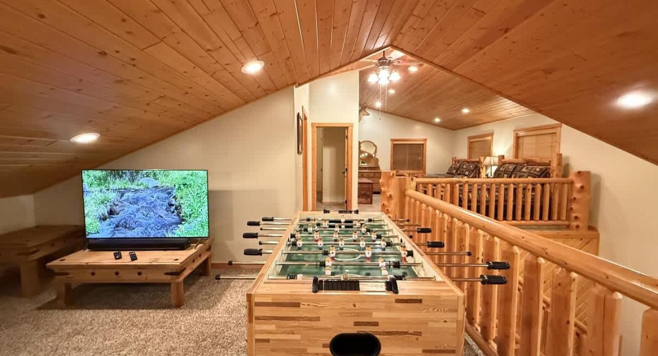 Upstairs loft area with tv, seating, and foosball table.