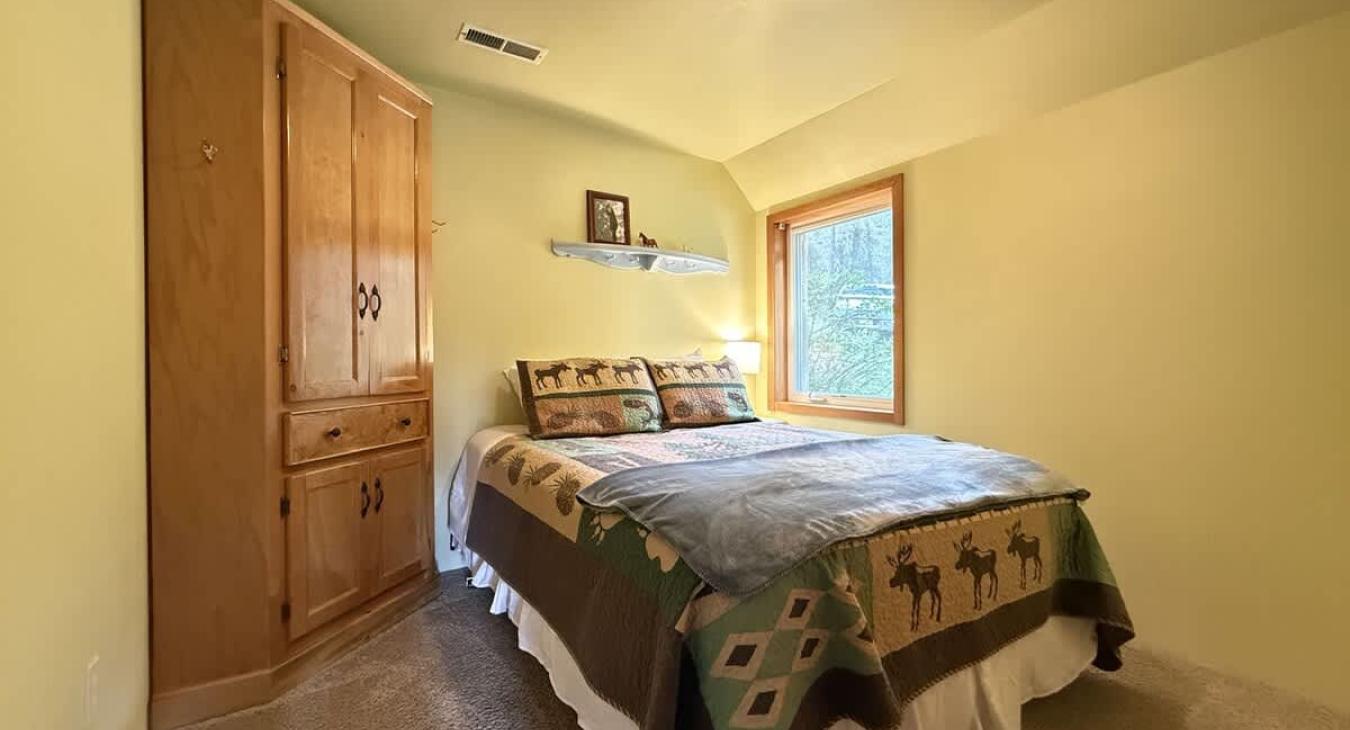 Bedroom complete with a bedside table, lamp, closet, and a window.