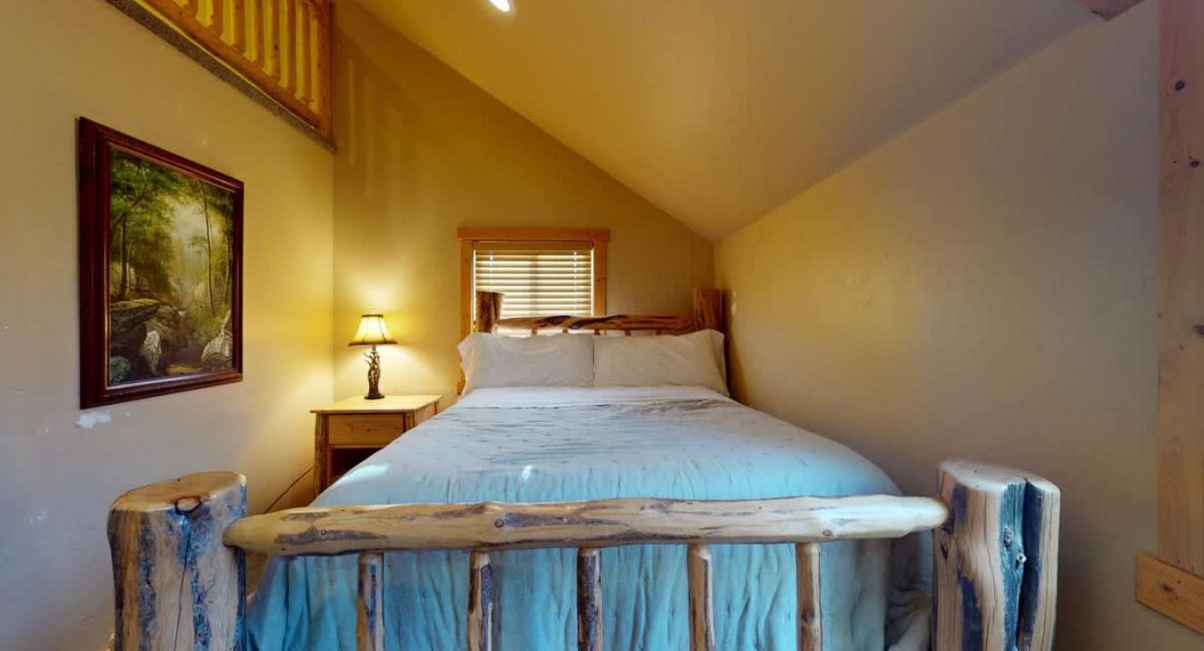 Queen size bed in the back corner of the room.