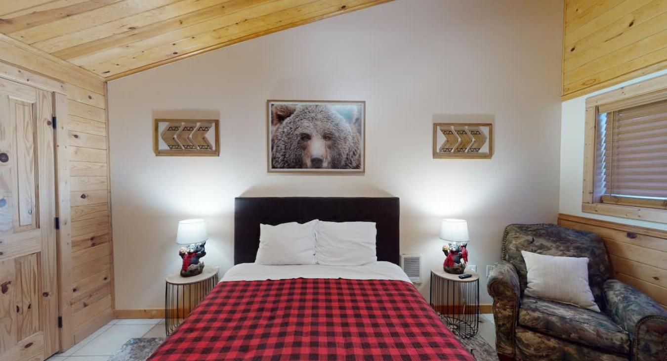 The bedroom has a queen bed, additional seating, and a large window to enjoy the beautiful landscape.