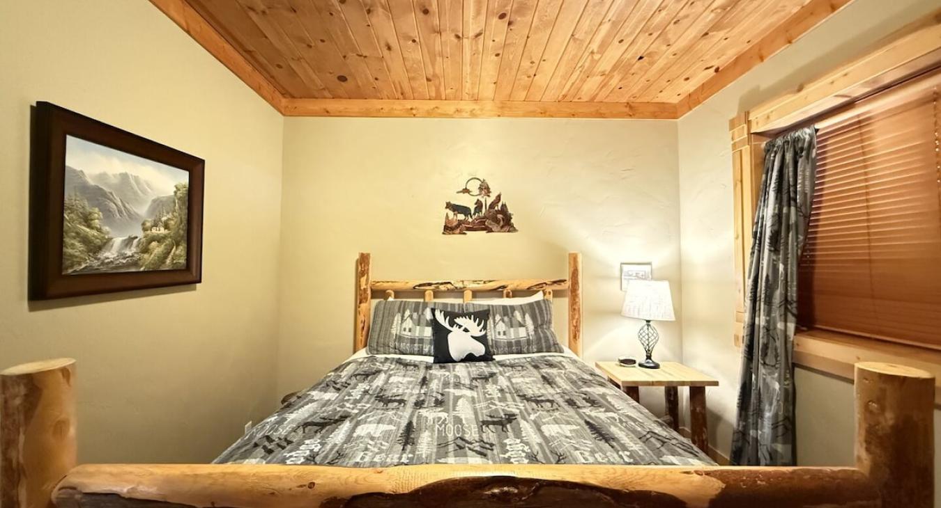 Bedroom #3 located in the basement with a queen bed right off the living room.