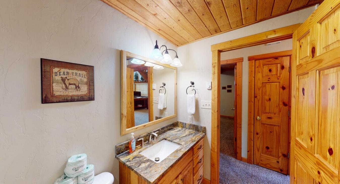 Bathroom equipped with shower tub combo, toilet, and sink vanity.