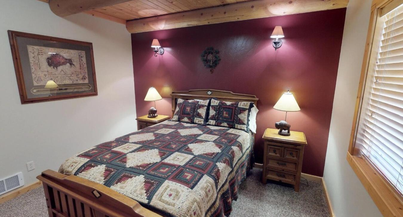 On either side of the bed are matching wooden nightstands, each topped with a simple lamp.