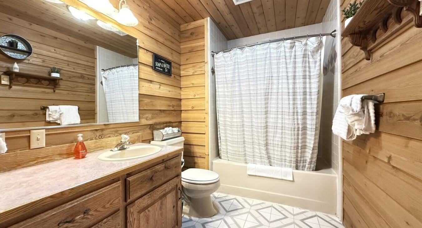 Full size bathroom with a tub shower combo, toilet, and sink.