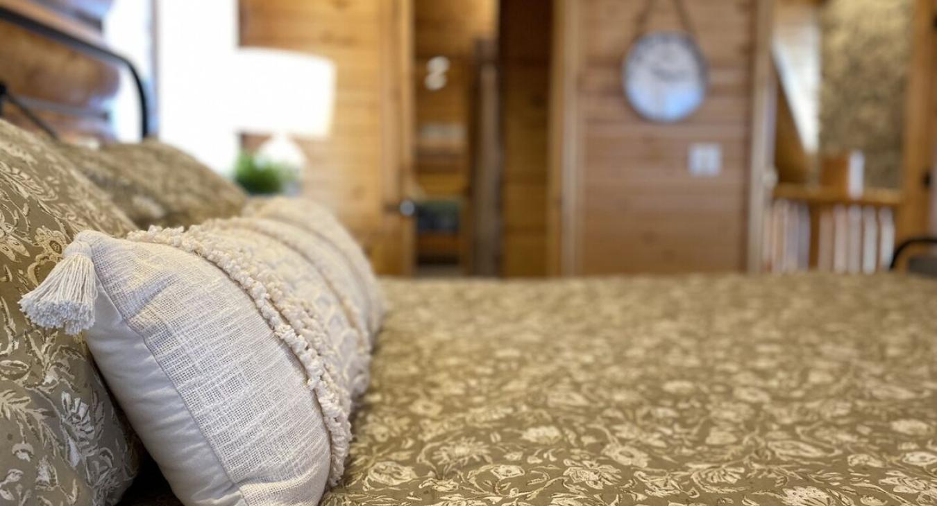 At the center of the room is a large, king-sized bed. The bed is positioned to offer a perfect view of the room and the stunning outdoor landscape just beyond.