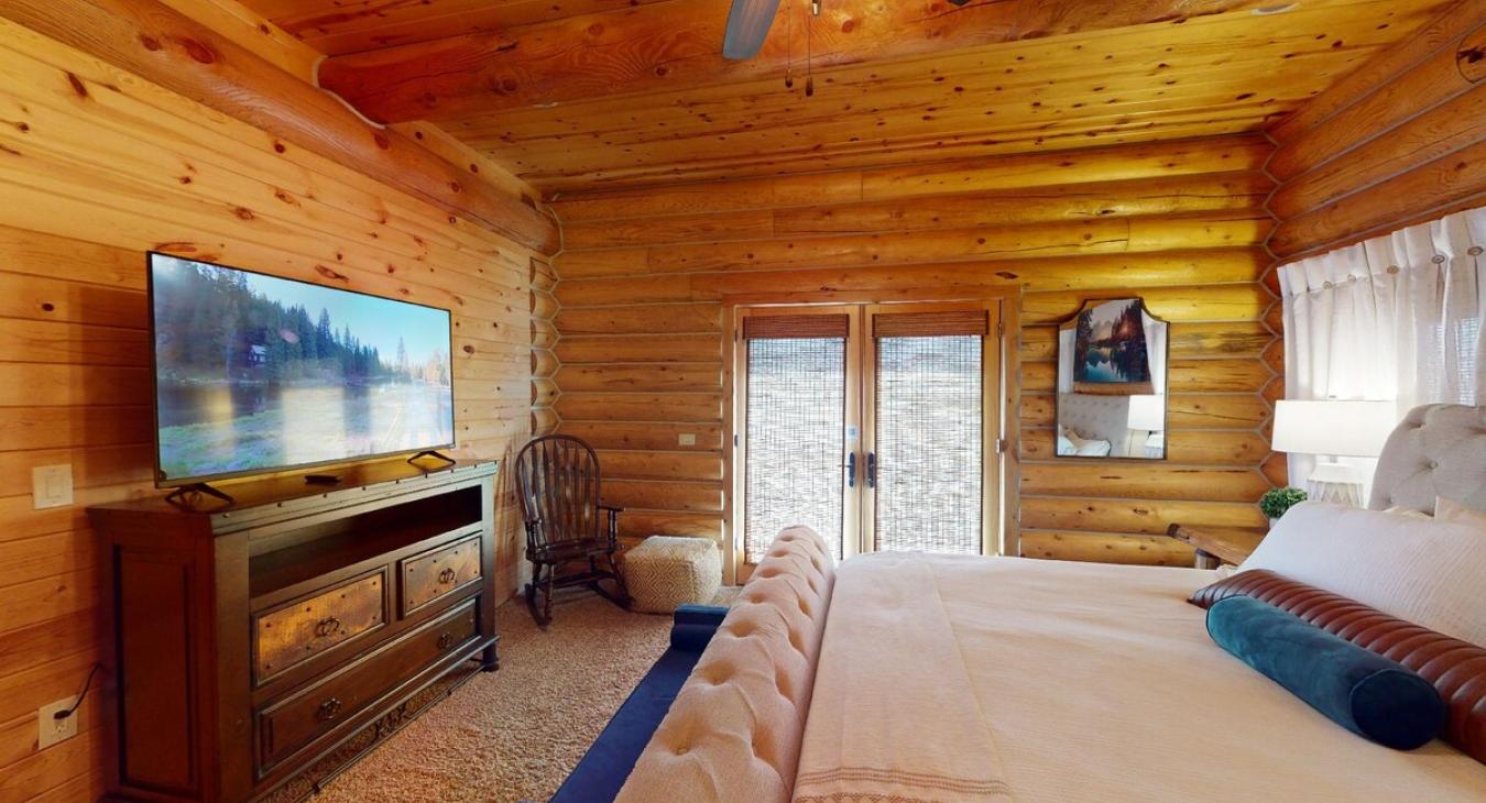 On one side of the room, there are French doors leading to a private deck. The deck, made of smooth wood, extends into the backyard, offering a peaceful space to unwind.
