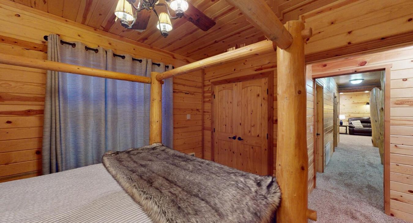 The first bedroom in the basement has a warm, inviting feel, with the walls adorned in rich, natural wood paneling, which gives it that quintessential cabin vibe.