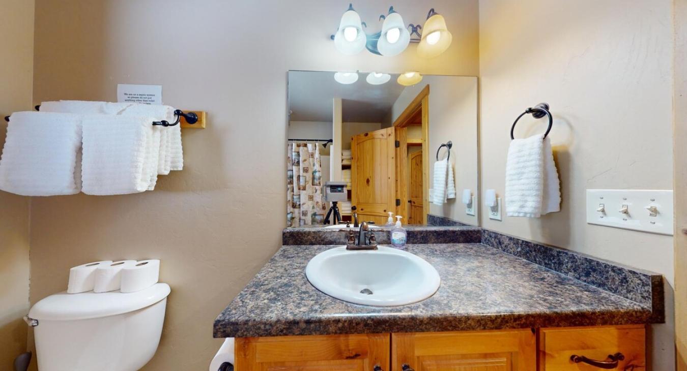 Equipped with shower tub combo, toilet, and sink vanity.