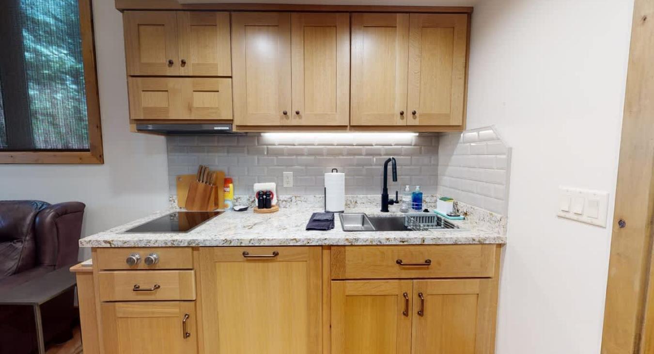 The compact kitchen featuring a stovetop, large sink, and plenty of cupboard space.
