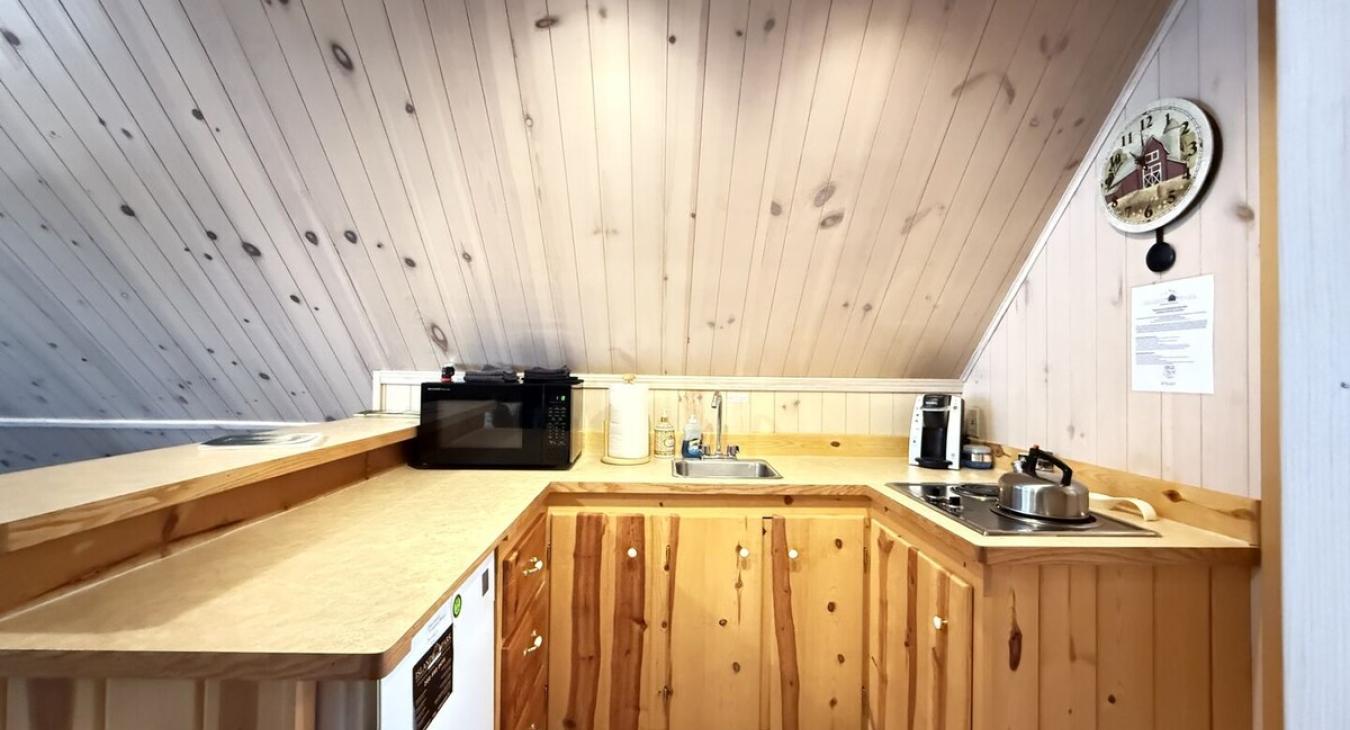Kitchen equipped with mini fridge, basic cookware, dishes, and silverware.