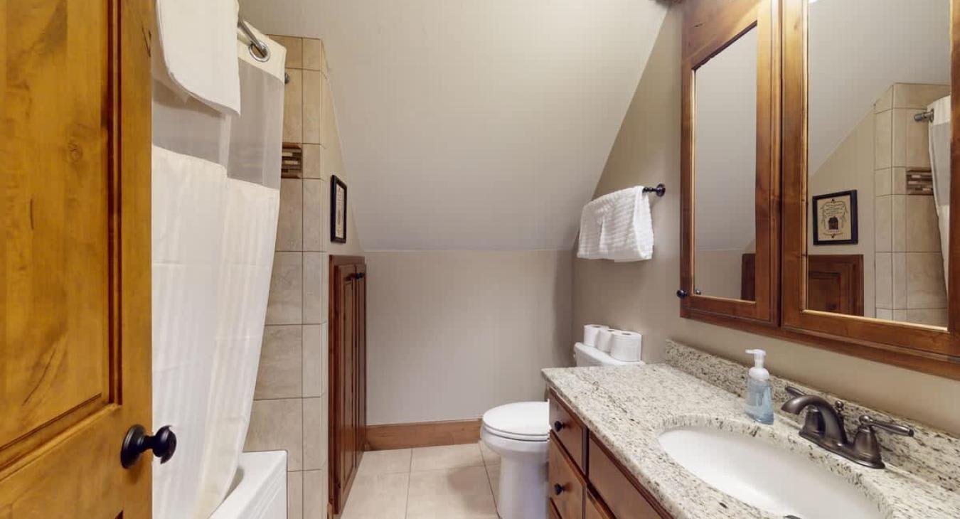 Upstairs shared bathroom with shower and tub combo, toilet, and sink vanity.