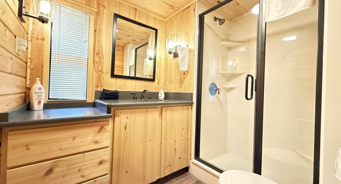 The bathroom is spacious and serene, blending the rustic elegance of the cabin with a touch of spa-like comfort.