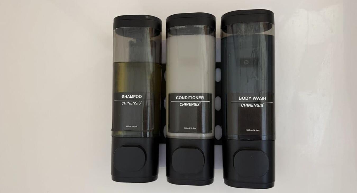 Shampoo, conditioner, and body wash dispensers are located in the shower.