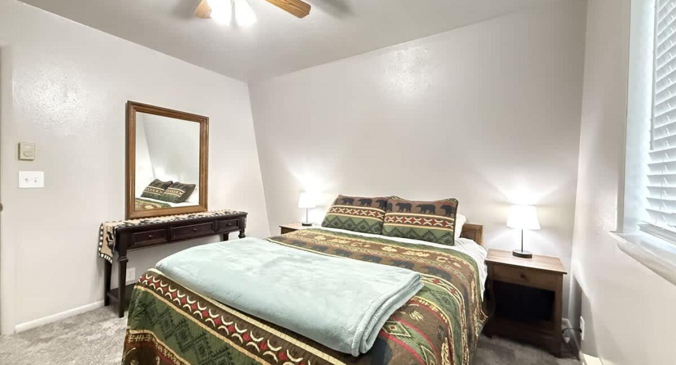 This bedroom features 1 queen bed that will comfortably sleep 2 guests. It also has a window overlooking the beautiful scenery of the cabin.