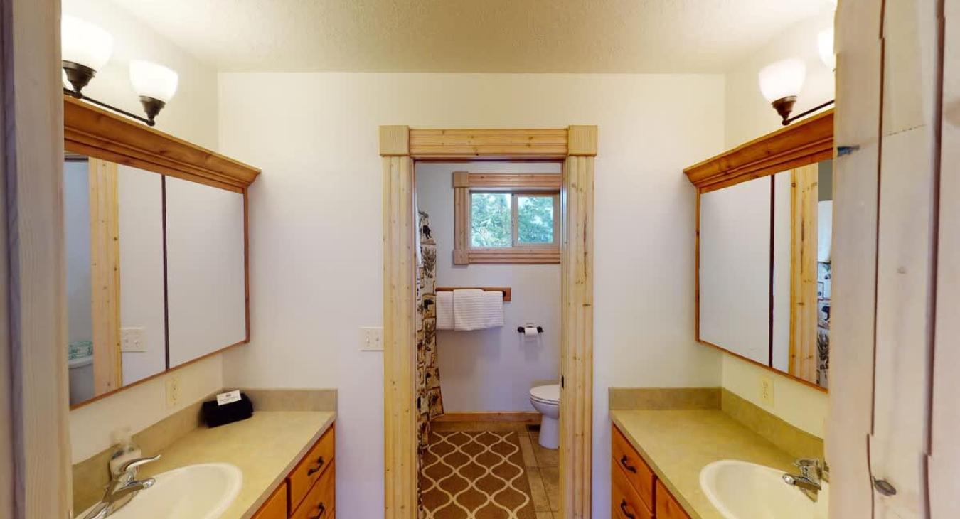 Full size bathroom located upstairs with shower/tub combo, toilet, and two sets of sink vanities.
