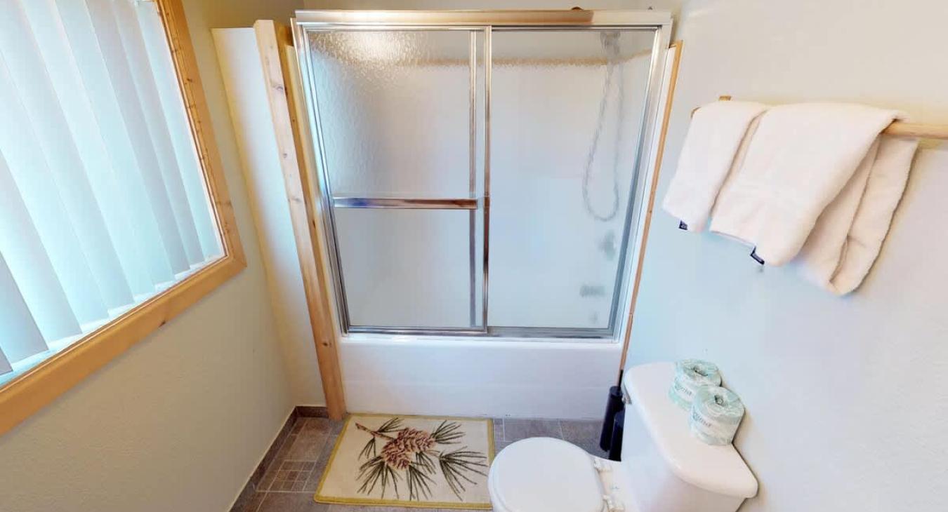 Main level shared bathroom with shower/tub combo, toilet, and sink vanity.