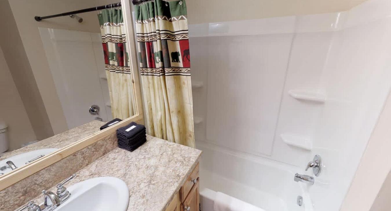 Basement shared bathroom with shower tub combo, toilet, and sink vanity.