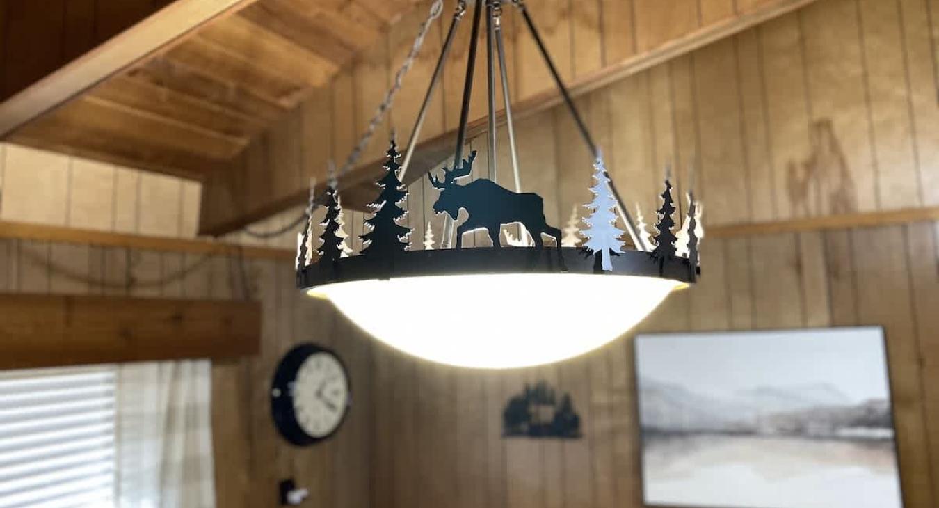 Light fixture with pine trees and moose that you might see.