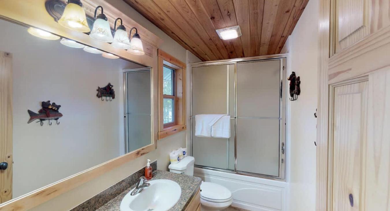 Main level bathroom with a shower tub combo, toilet, and sink vanity.