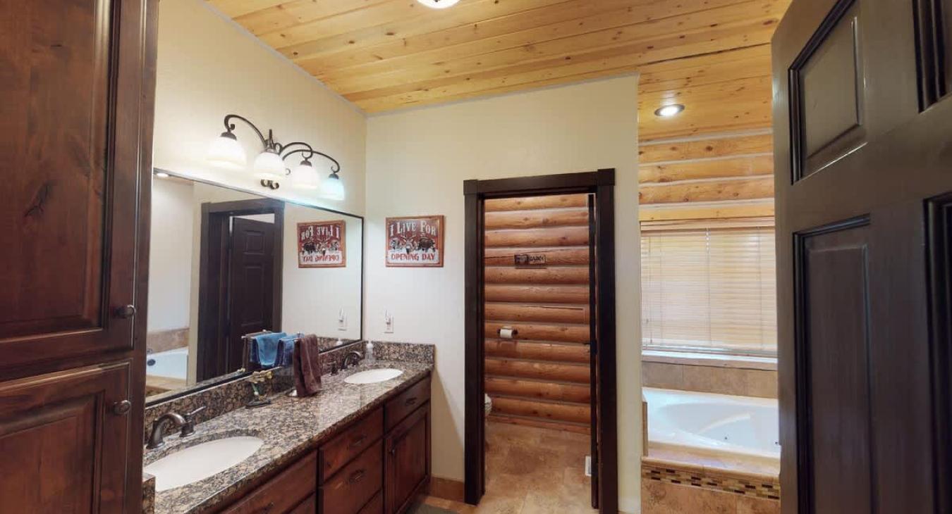 This bathroom is equipped with a tub, standing shower, toilet, and double sink vanity.