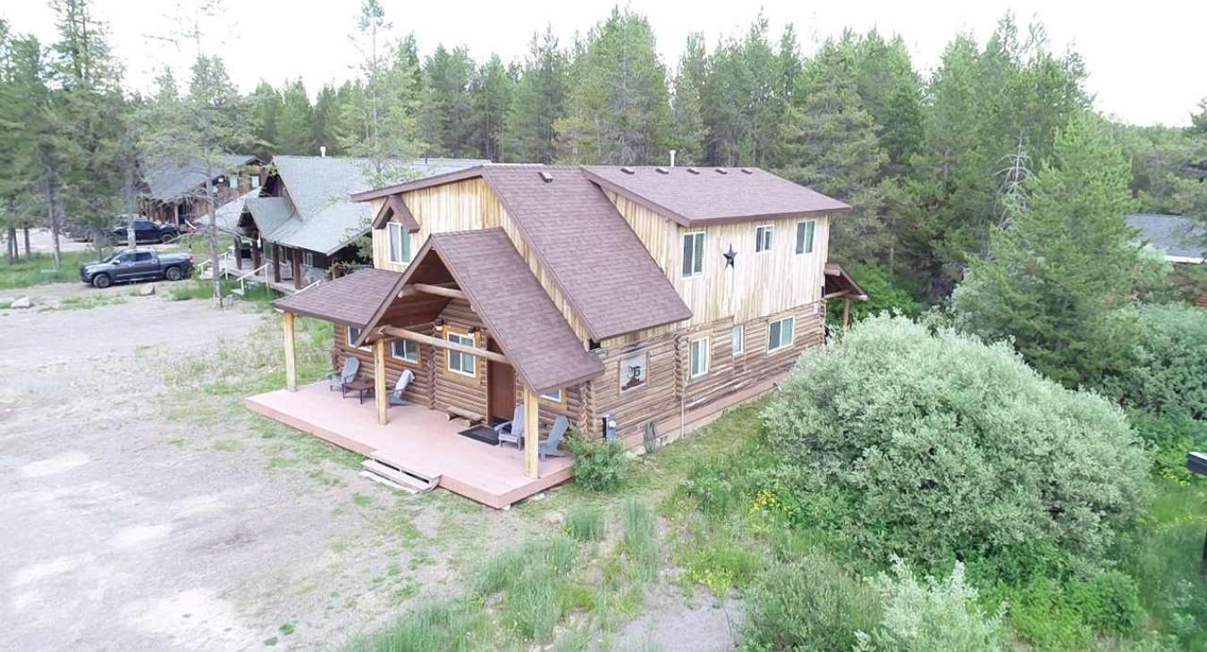 This beautiful aerial drone shot showcases the full scale of the authentic log home and the private, forested surroundings of the property.