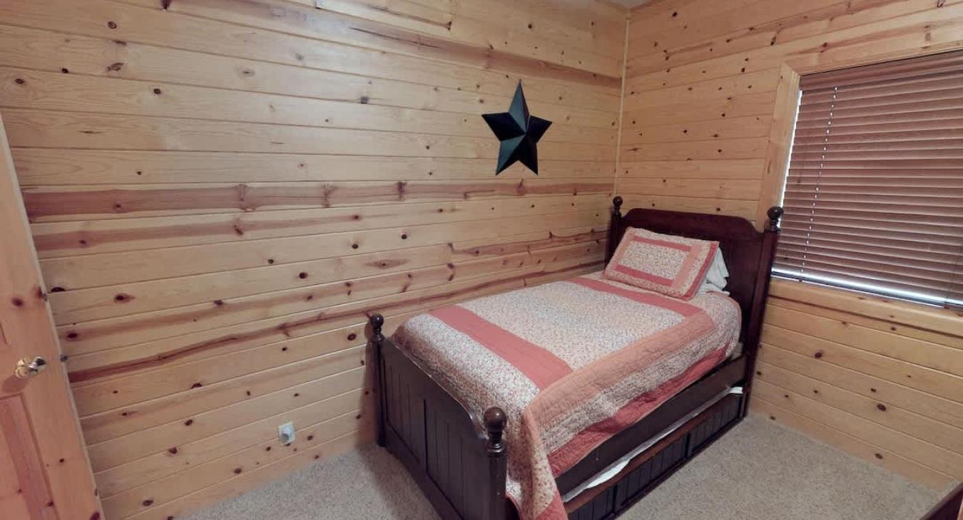 Twin bed in the kid's bedroom with a trundle bed located underneath.