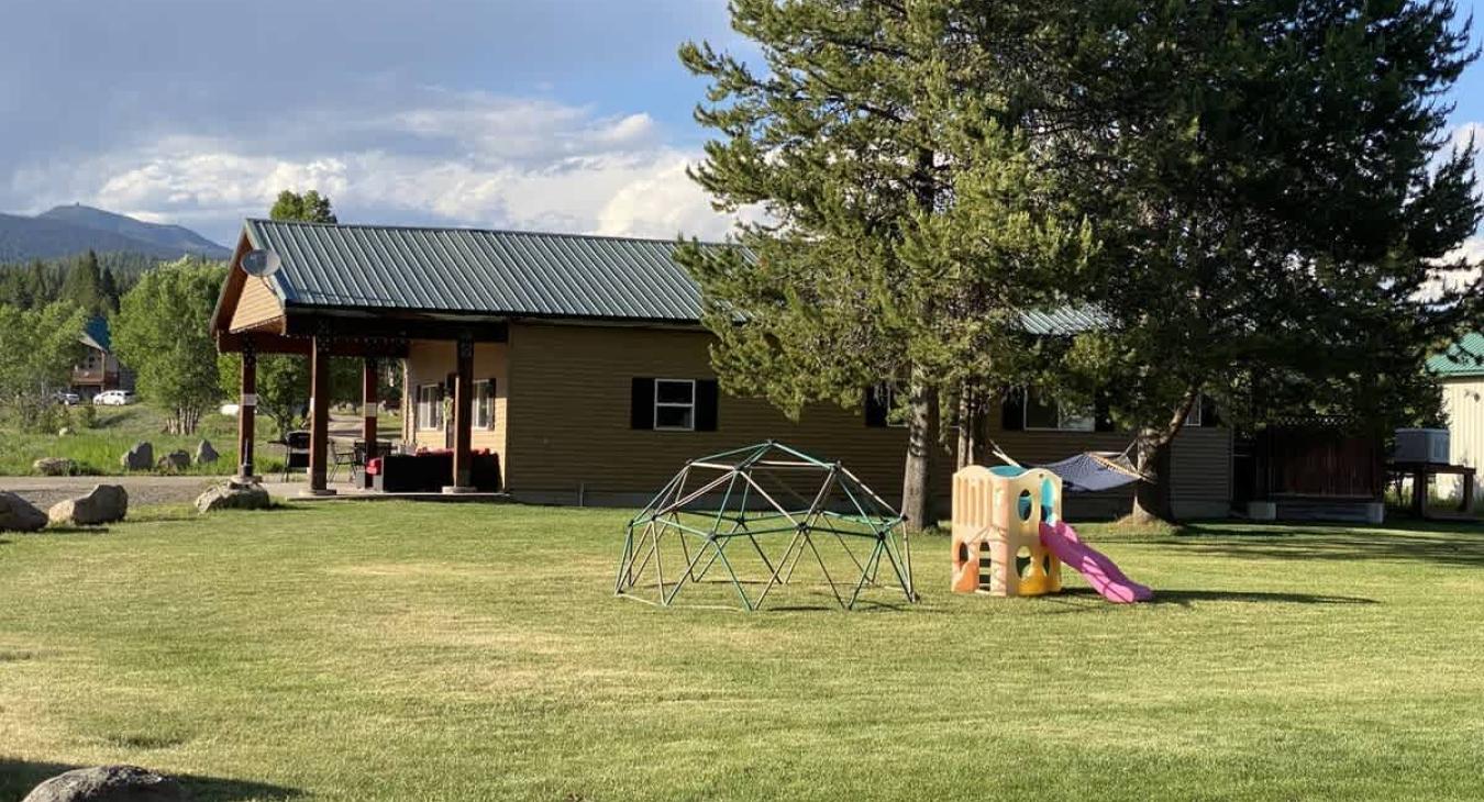 Large grass area and small play set is located adjacent to the cabin.