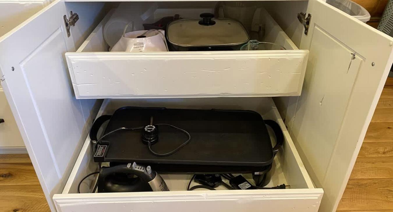 Within the lower cabinets, various appliances are neatly stored, each one easily accessible yet discreetly tucked away when not in use. There is a griddle, blender, hand mixer, and warming dish.