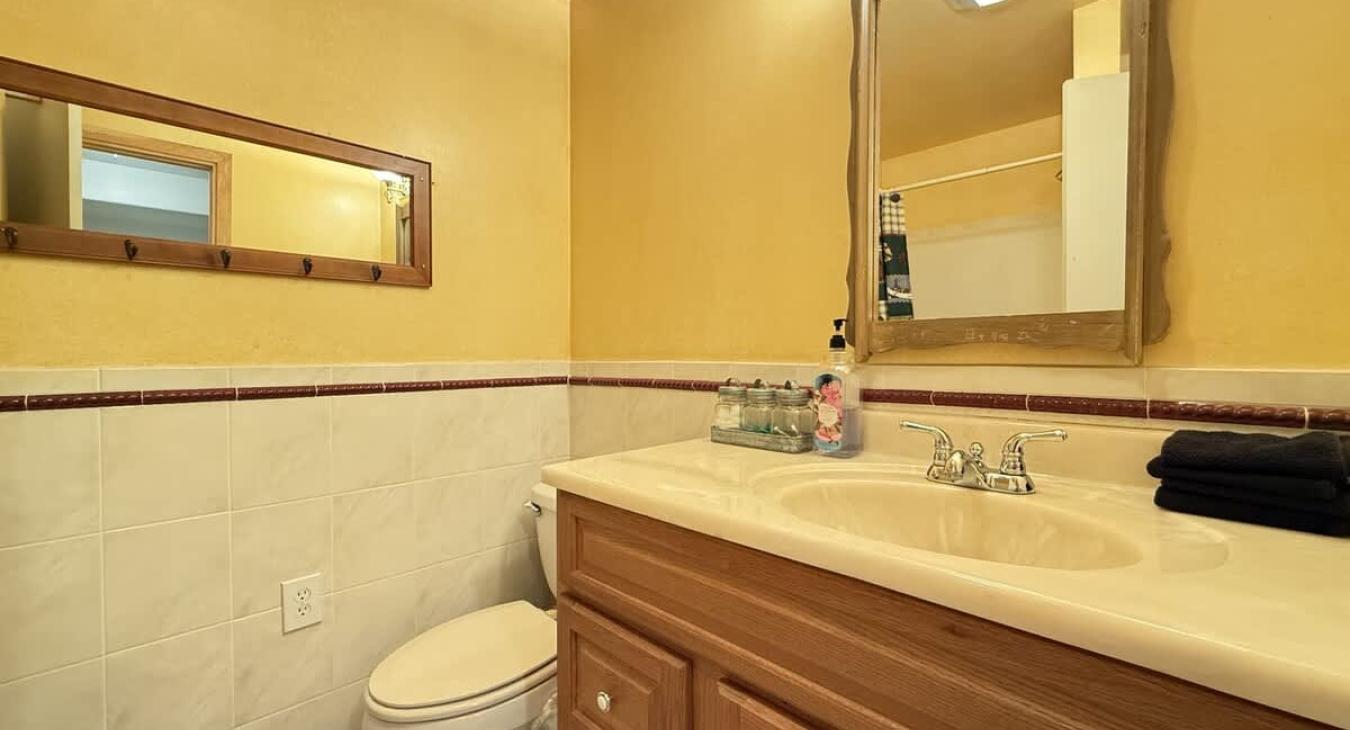 Full bathroom in the basement with shower tub combo, sink, toilet, and vanity storage. Towels are provided.