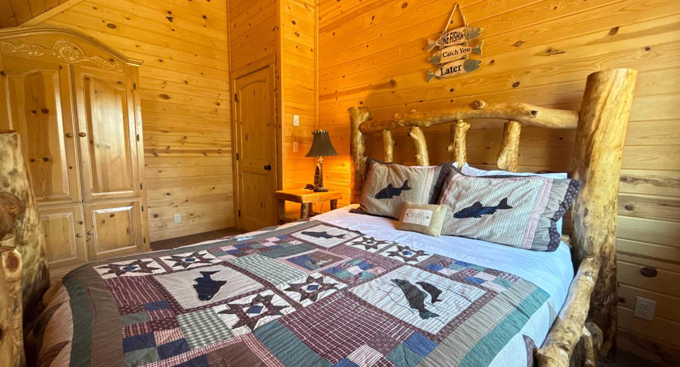 Designed for ultimate group comfort, this sprawling guest suite showcases a master-crafted log Queen bed styled with a rich wilderness quilt and paired with a classic wooden armoire.