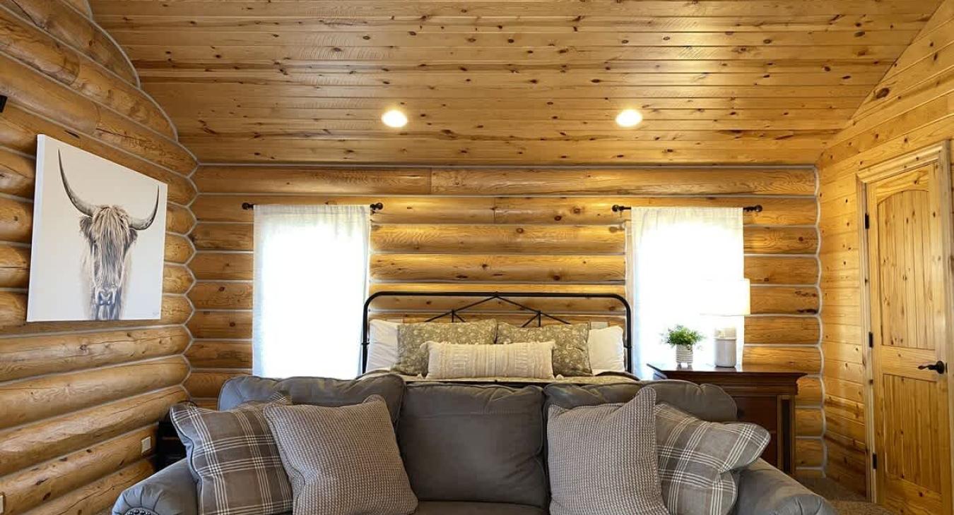 The upstairs bedroom in the cabin is a serene retreat, offering a perfect blend of rustic charm and comfort. The walls are made of natural wood, with the rich grains and warm tones of the timber adding to the cozy, inviting atmosphere.