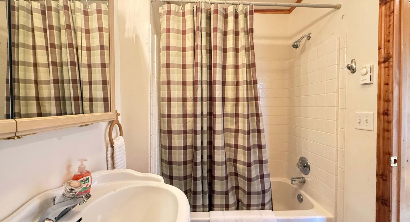 Shared bathroom on the main level with shower tub combo, toilet, and sink.