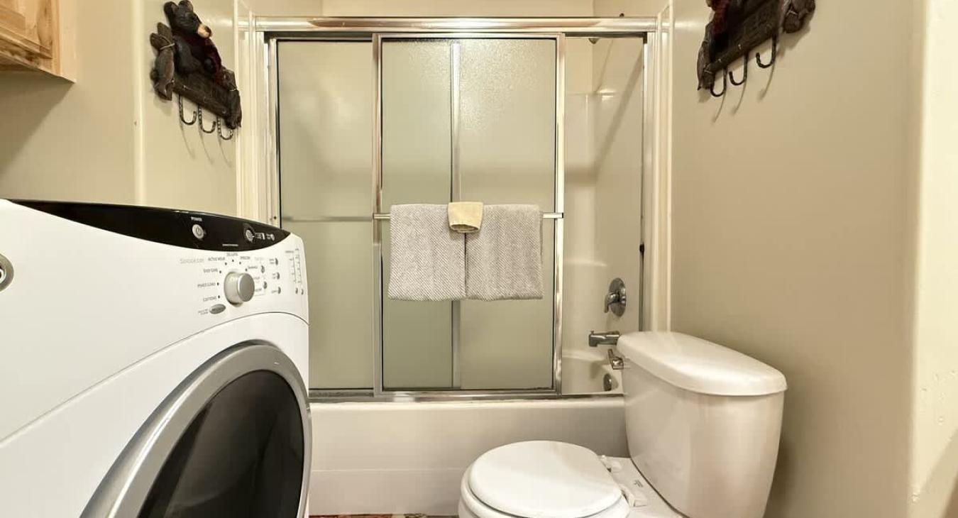 Basement shared bathroom with shower tub combo, toilet, and sink vanity.