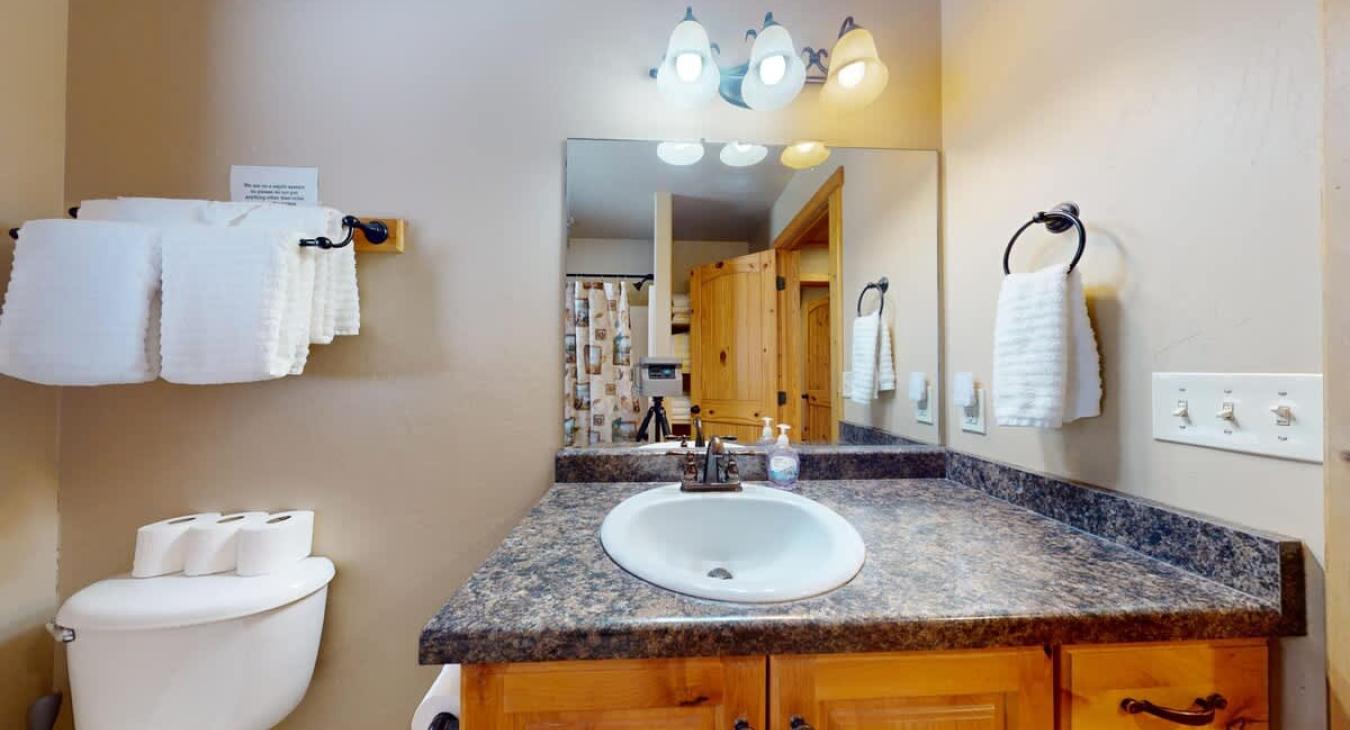 Equipped with shower tub combo, toilet, and sink vanity.