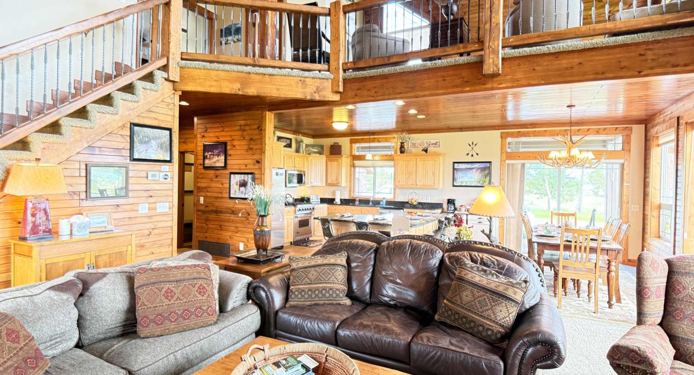 The living room offers a welcome environment to relax after a long day and connect with others. An open and inviting great room with comfortable leather seating, connecting the kitchen, dining area, and upper loft seamlessy.