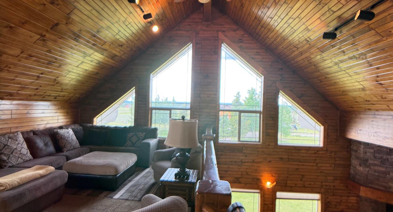 Enjoy the ultimate cabin vibe in this cozy upper loft, nestled under dramatic sloped wood ceilings with track lighting and endless charm.