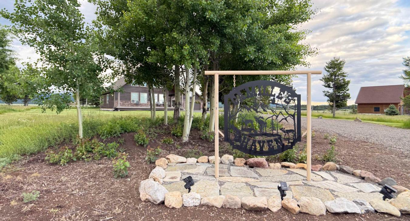 Welcome to Camille's Haven! Look for our beautifully crafted metal property sign framed by lush green trees at the entrance.