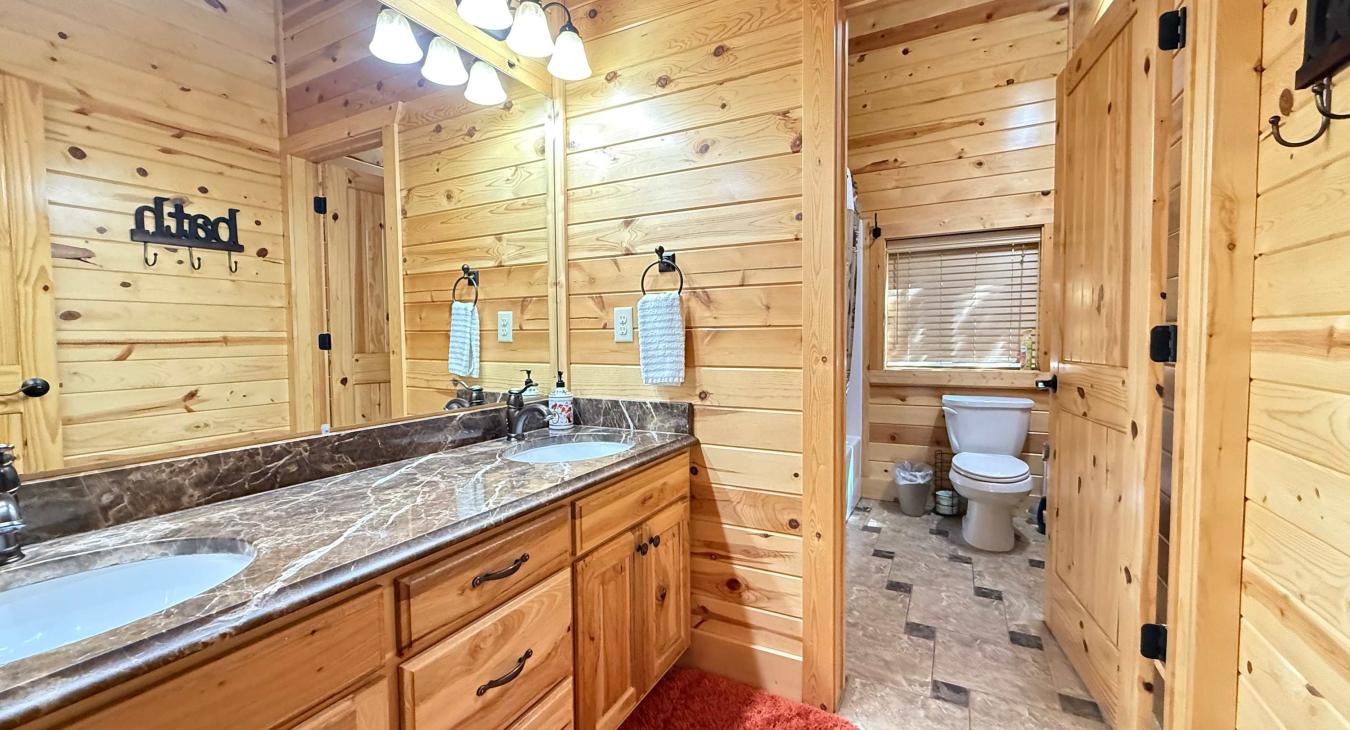The large upstairs shared bathroom features a double-sink marble vanity and plenty of mirror space, leading into a separate toilet and shower area.
