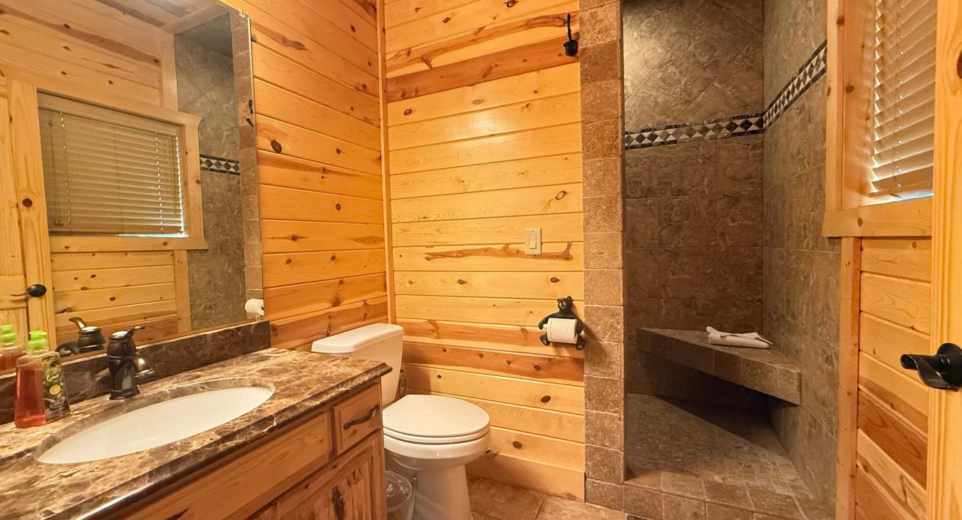 The master suite features a private 3/4 ensuite bathroom complete with a marble-top vanity, toilet, and a spacious custom tile shower.