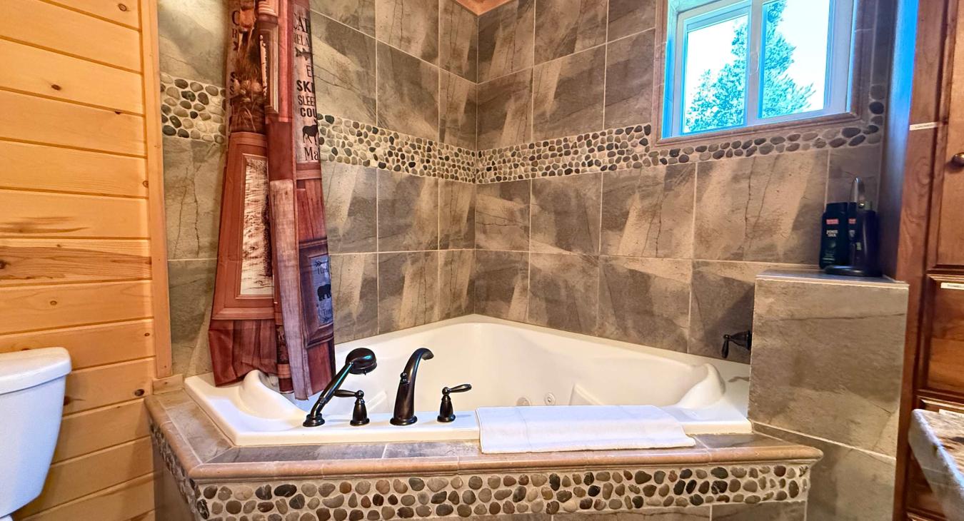 Unwind after a day of outdoor adventures in the deep jetted tub, beautifully styled with custom river-rock tiling and a premium overhead rain shower.