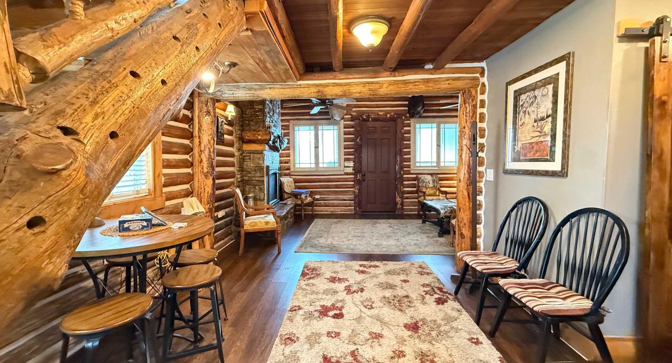A charmingly designed open floor plan features a rustic log staircase with a cozy bonus seating nook nestled perfectly underneath.